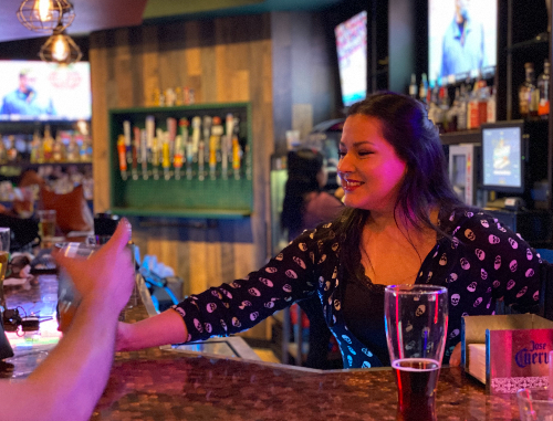 bartender giving drink to customer at bar